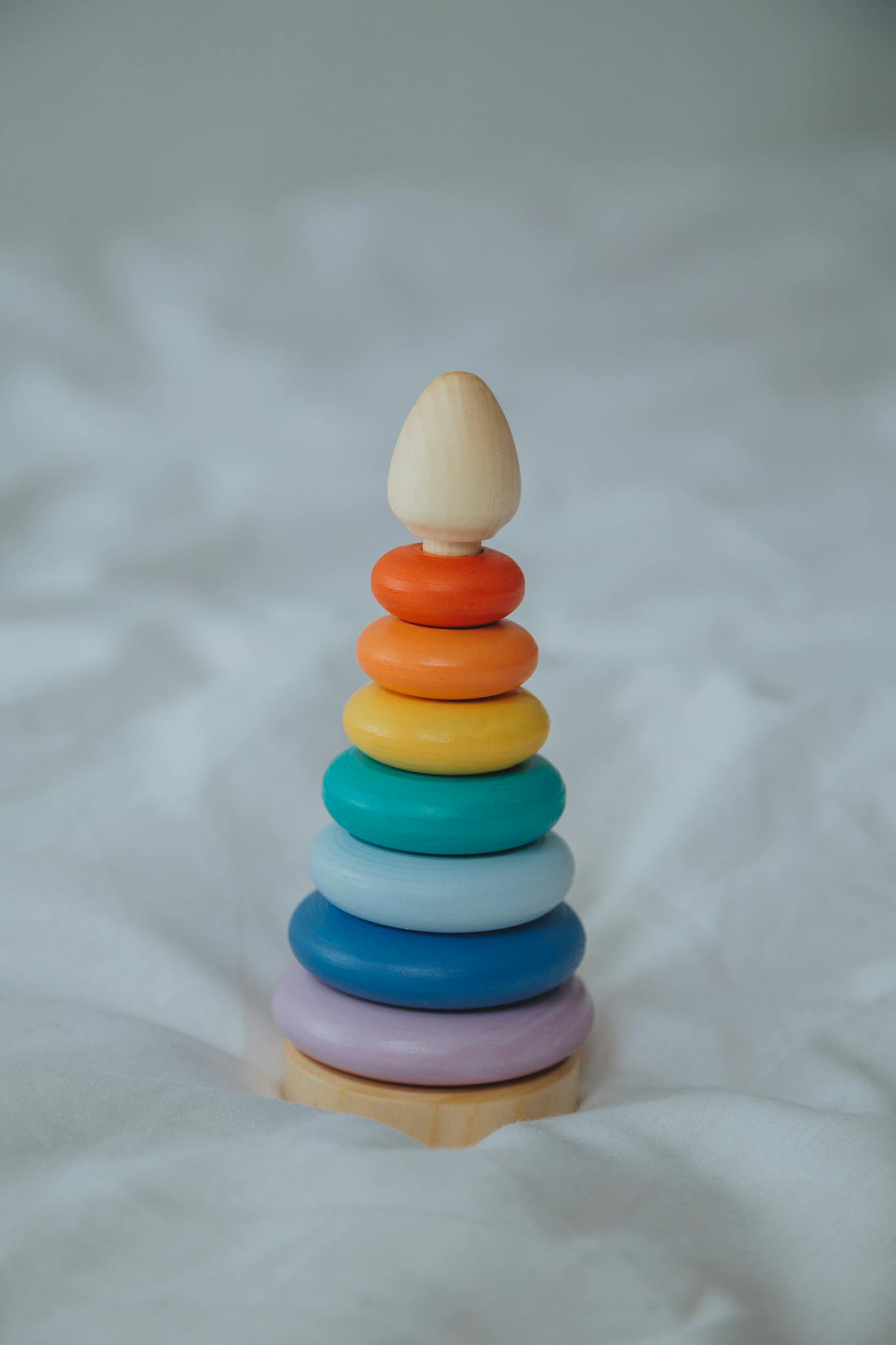 A colorful wooden stacking toy on a soft white background, perfect for child development.
