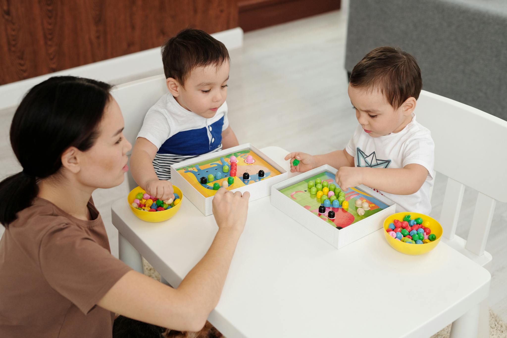 A mother and two young children enjoy a playtime session with colorful toys indoors.