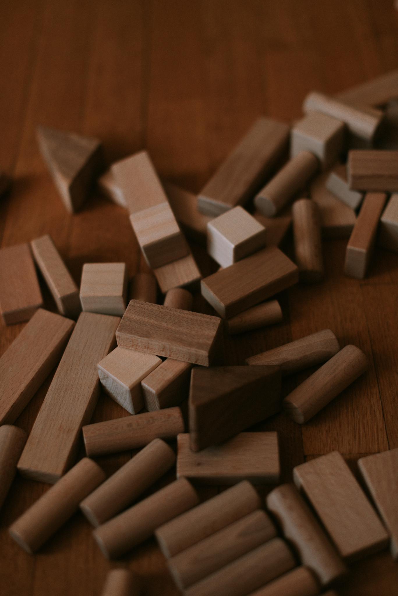 A scattered collection of natural wooden building blocks on a wooden surface.